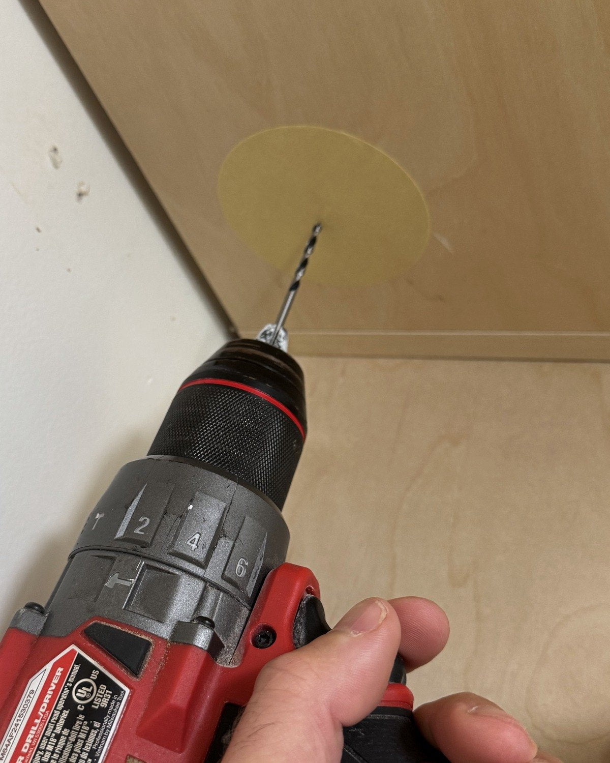 Drilling a pilot hole through the center of the tape dot