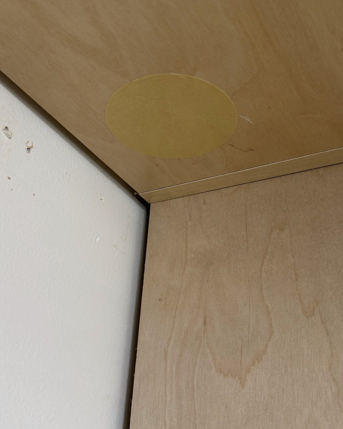 A masking tape dot pressed onto the panel where the hole will go